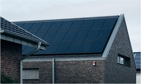 A modern brick house with a pitched roof covered in solar panels under an overcast sky.